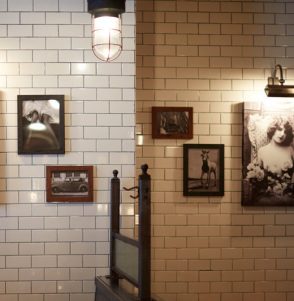 Wall covered in subway tiles and framed vintage photographs