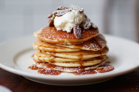 Pancakes topped with whipped ricotta, toasted pecans, salted caramel sauce