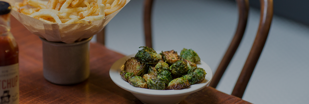 Roasted Brussel sprouts in a bowl next to french fries