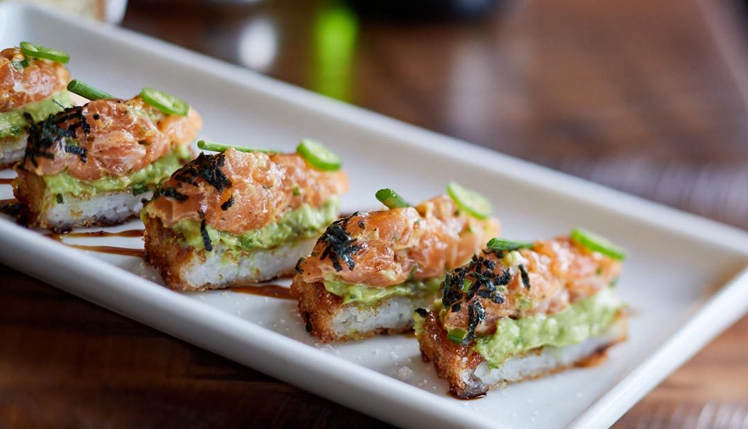 A photo of salmon tartare on top of avocado and crispy rice