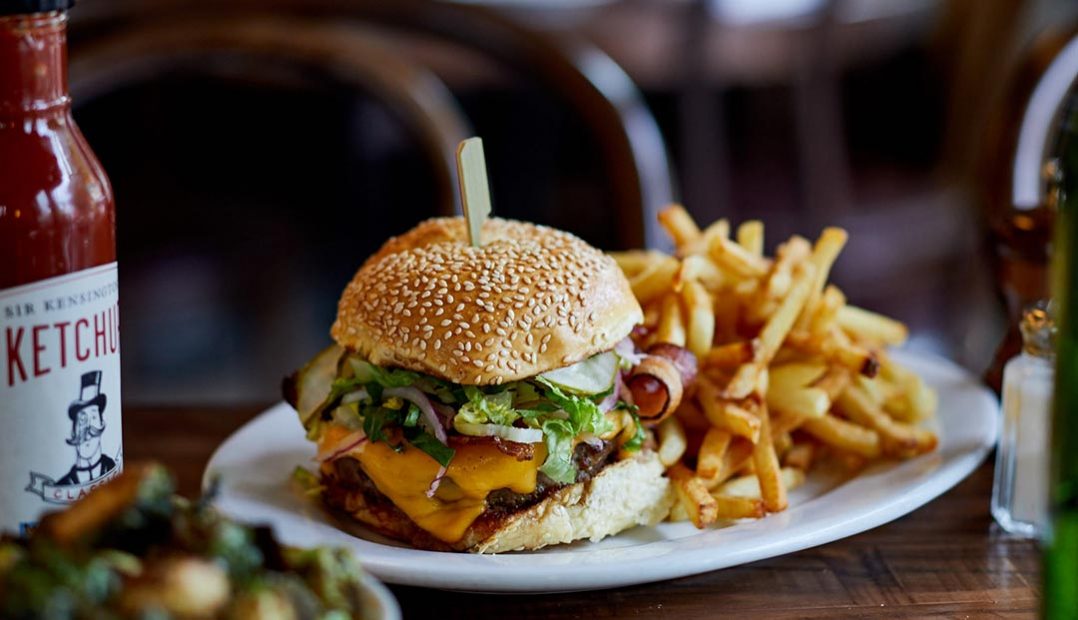 A photo of a cheeseburger with fries