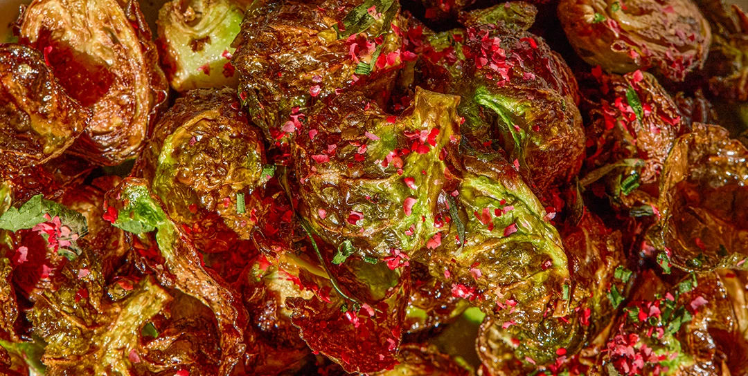 Close up image of crispy brussels sprouts with pink peppercorns